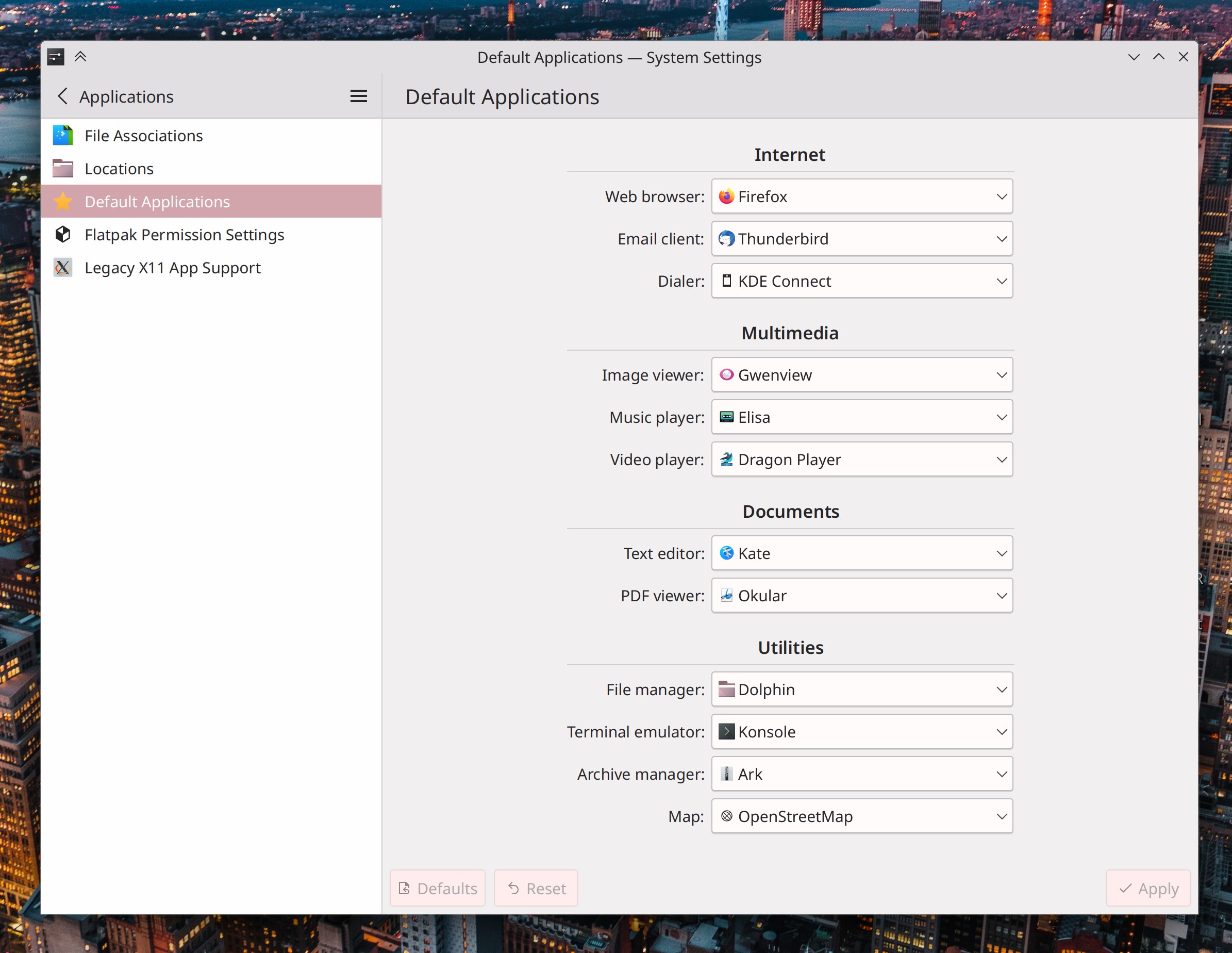 System Settings main window showing "Default Applications" page with large list of URL protocols and file formats that you can choose your preferred app for, including "Web browser," "Email client," "Dialer," "Image viewer," "Music player," "Video player," "Text editor," PDF viewer," File manager," Terminal emulator," "Archive manager," and "Map"